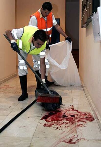 Dos trabajadores del servicio de limpieza del ayuntamiento de Las Palmas de Gran Canaria limpian el zaguán donde se ha producido el crimen.