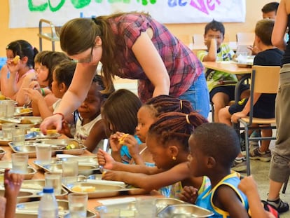 Un grupo de menores almuerza en el comedor escolar de verano.