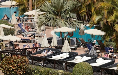 Varios turistas confinados en el hotel Costa Adeje Palace de Tenerife toman el sol con mascarillas, este miércoles.