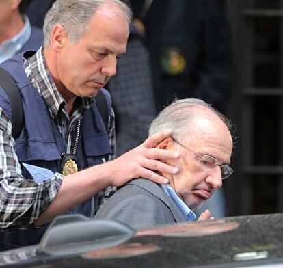 La Policía detiene a Rodrigo Rato tras haber registrado su casa en abril de 2015 por los presuntos delitos de blanqueo, alzamiento de bienes y fraude fiscal. Uno de los funcionarios le coge de la nuca para ayudarlo a entrar al coche.