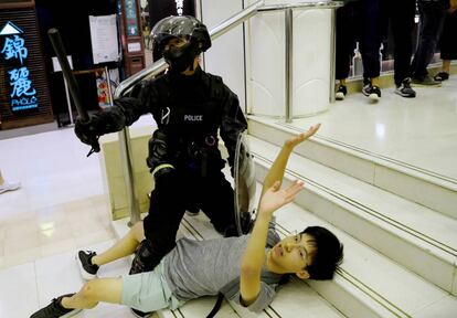 Un policía detiene este domingo a un joven en el centro comercial de Tai Po.