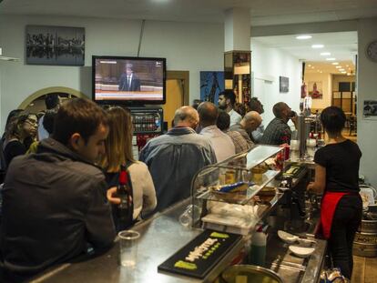 Ciudadanos escuchan el discurso del presidente de la Generalitat, Carles Puigdemont, en un bar cerca del Parlament.