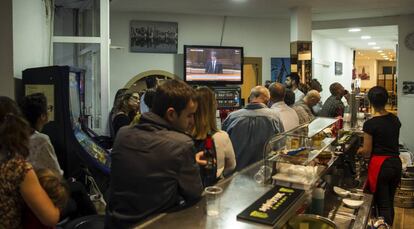 Ciudadanos escuchan el discurso del presidente de la Generalitat, Carles Puigdemont, en un bar cerca del Parlament.