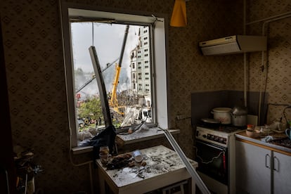 Interior de una vivienda afectada por el bombardeo ruso en la ciudad ucrania de Uman. Al fondo, bomberos trabajan en la búsqueda de supervivientes.