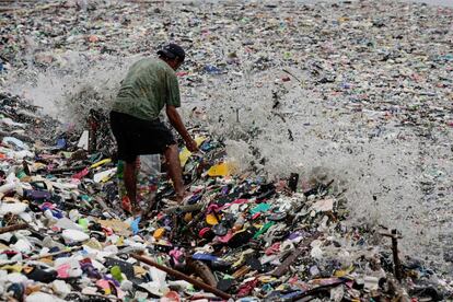 Un hombre busca materiales y objetos reutilizables entre la basura que fue arrastrada hasta la orilla en la bahía de Manila tras el paso de una tormenta tropical, en Manila (Filipinas).