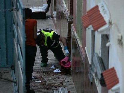 La Policía científica examina pruebas en la puerta de la vivienda de Alzira donde se ha producido el tiroteo.