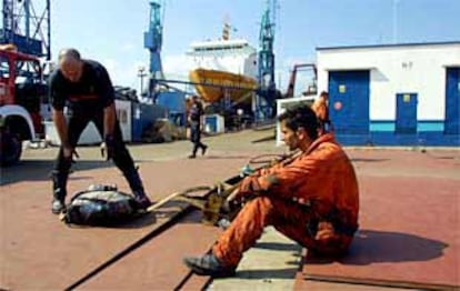 Bomberos y trabajadores, después de las labores de extinción del incendio en un barco en los astilleros de Vigo.