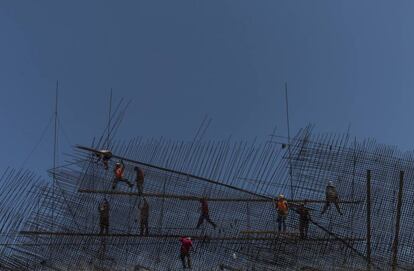 Un grupo de trabajadores de la construcción laboran sobre un puente carretero.