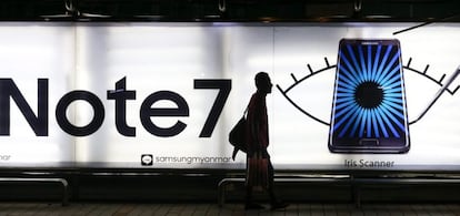 Un hombre camina junto a una parada de autob&uacute;s en la que aparece una publicidad del Galaxy Note 7 de Samsung.