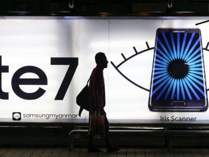 Un hombre camina junto a una parada de autob&uacute;s en la que aparece una publicidad del Galaxy Note 7 de Samsung.