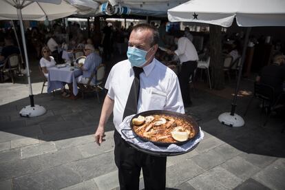 Un camarero del restaurante Salamanca, en la Barceloneta, sirve una paella en la terraza del local