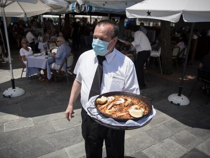 Un camarero del restaurante Salamanca, en la Barceloneta, sirve una paella en la terraza del local
