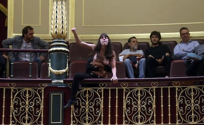 Una ujier abraza por la espalda a la última de las tres activistas, que sigue encaramada a la barandilla de la tribuna de invitados.