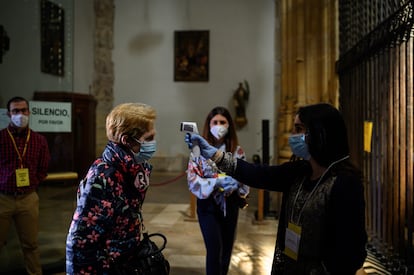 Una mujer toma la temperatura a otra en las puertas de la catedral de Alcalá de Henares el 3 de mayo