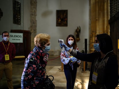 Una mujer toma la temperatura a otra en las puertas de la catedral de Alcalá de Henares el 3 de mayo