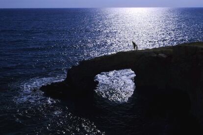 Un hombre y un niño caminan sobre el llamado 'puente del amor' en el cabo Greco de Chipre.