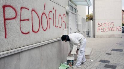 Un pintor cubre una pintada en la parroquia donde ejercía el padre Román, en 2014.