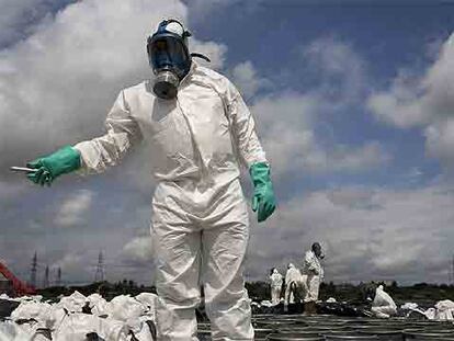 Especialistas en el tratamiento de tóxicos protegidos con máscara antigás limpian el lugar contaminado en las afueras de Abiyán.