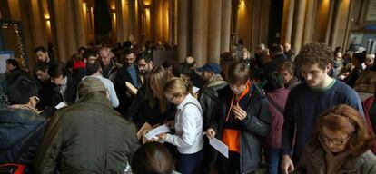 Los ciudadanos escogen las papeletas para ejercer su voto en las elecciones generales, antes de incorporarse a la cola en el colegio electoral situado en la Universitat de Barcelona. EFE/Toni Albir