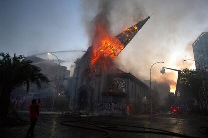 Un hombre toma fotografías mientras colapsa la torre de la iglesia.