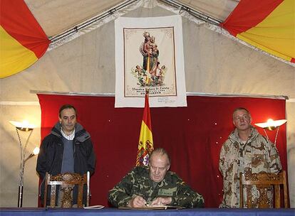 El rey Juan Carlos, acompañado del minstro de Defensa, José Antonio Alonso, y el coronel José Antonio Camiña Conesa, mando de la Base de Apoyo Avanzado de Herat, firma en el libro de honor de la base multinacional.