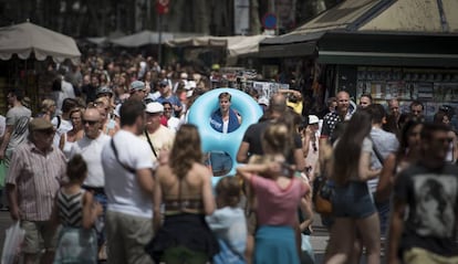 Un turista con flotador y toalla al hombro baja por las Ramblas.