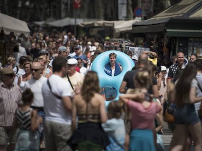 Un turista con flotador y toalla al hombro baja por las Ramblas.