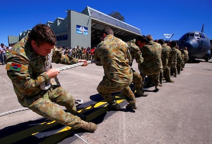 Miembros del Ejército de Defensa Australiana tiran de un avión C-130J en la base militar de Richmond.

