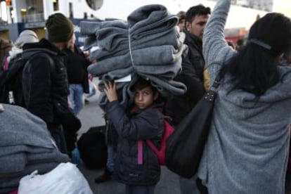 Un nen trasllada mantes després de la seva arribada amb altres centenars de refugiats al port del Pireu.