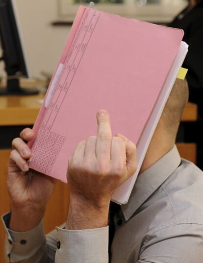 Edis Kalayar hace una peineta mientras se cubre el rostro con una carpeta durante su juicio en los juzgados de la localidad alemana de Kirchheim unter Teck, el 9 de marzo de 2010