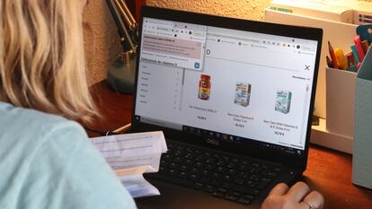 Una jovne compra vitamina D en una farmacia online desde su casa.