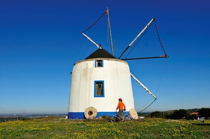 Nos vamos hacia el sur. Si cruzamos la frontera portuguesa desde Rosal de la Frontera, en la sierra de Aracena (Huelva), descubrimos una de las regiones más auténticas de Portugal, el Alentejo interior, tranquilo, rural, apacible y silencioso. A media hora de la Raya podemos parar en Serpa, un apacible pueblo rodeado de colinas, viñedos y campos polvorientos, de calles estrechas y adoquinadas y casas blancas. Es la esencia de la vida alentejana: en su corazón medieval, rodeado casi totalmente por murallas y por los impresionantes arcos de un acueducto del siglo XI, hay una placita muy agradable donde suelen citarse los ancianos a tomar el aire y el sol. No falta el castillo habitual de todos los pueblos fronterizos, con unas vistas impresionantes desde sus almenas. Serpa es famoso por la buena comida tradicional y hay varias fábricas que producen la joya culinaria local: el queso de Serpa, elaborado con cuajo de oveja.