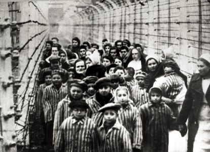 Un grupo de niños judíos supervivientes de Auschwitz, junto a una enfermera, detrás de una valla de alambre en Polonia en febrero de 1945.