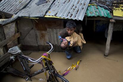 Un hombre traslada a un niño tras ser inundada su casa en un barrio de Srinagar, Cachemira. Al menos 41 personas han muerto y otras 8.700 se han visto afectadas por las inundaciones que se registran en el estado de Gujarat, en el oeste de India.