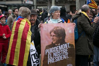 Una manifestante porta un cartel con el retrato del expresidente de la Generalitat, Carles Puigdemont, por el centro de Barcelona.