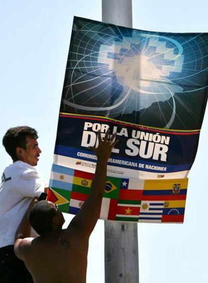 Dos trabajadores ponen un cartel de la I Cumbre Energética Suramericana en la venezolana Isla de Margarita.