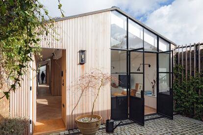 El acero, el cristal y la madera crean un hermoso tapiz de materiales que conforman la fachada de la casa. Las puertas de cristal con marcos de acero que comunican el salón con el patio de entrada consiguen llevar una gran cantidad de luz natural a cada rincón de esta vivienda.