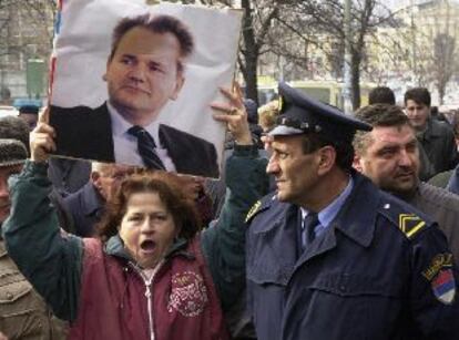 Un policía observa a una simpatizante comunista que exhibe un cartel del ex presidente Milosevic.