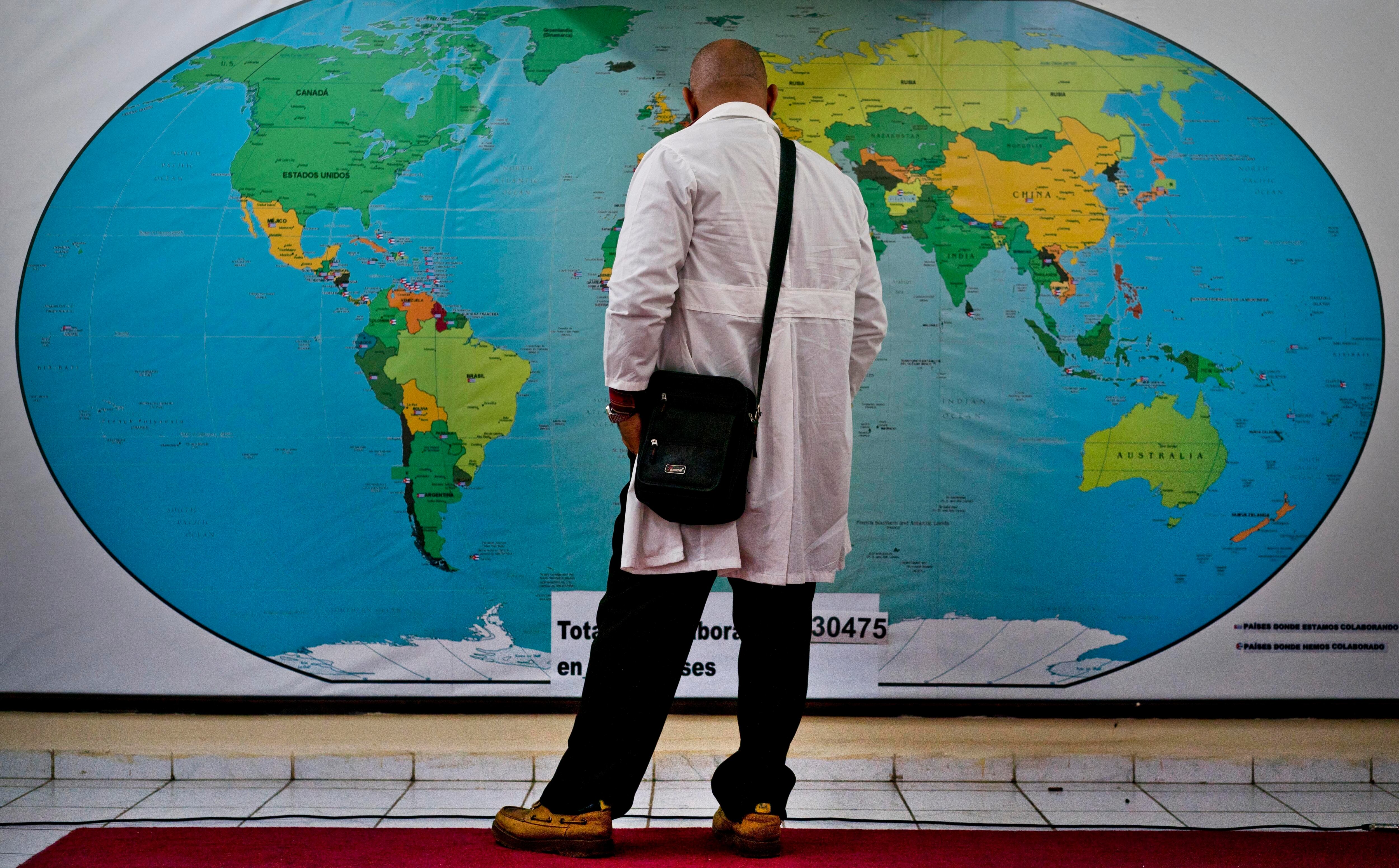 Un médico en La Habana mira un mapa de los sitios donde hay misiones médicas cubanas, antes de partir hacia Mozambique, en 2019.