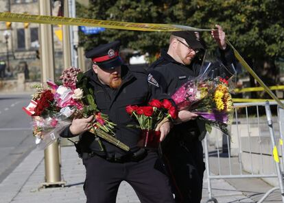 Agentes de policía llevan ramos de flores al monumento a los caídos de Ottawa, el 23 de octubre de 2014, el 23 de octubre de 2014.