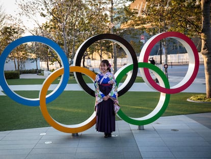 Japonesa vestida com um quimono diante dos anéis olímpicos de Tóquio