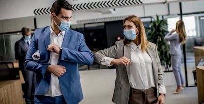 Dos trabajadores se saludan usando los codos.
