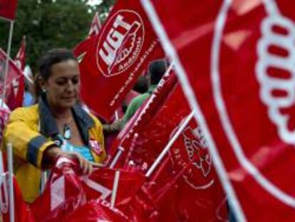 Una mujer prepara las banderas de los sindicatos en una concentración. EFE/Archivo