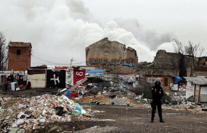 Un agente vigila esta mañana la zona afectada por el fuego, cuyo humo se ve a su espalda.