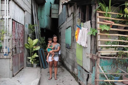 Jomarie Malonzo Palma, de 24 años, con su hijo delante de su hogar en Valenzuela, un distrito de Manila (Filipinas).