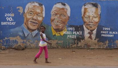 Una niña pasa ante retratos de Mandela en Soweto este jueves.