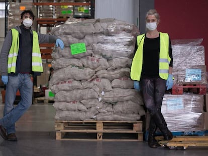 Dos colaboradores de los Bancos de Alimentos en un almacén con comida empaquetada para ser repartida.