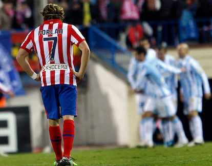 Forlán, tras el segundo gol del Málaga, cuyos jugadores, al fondo, lo celebran.