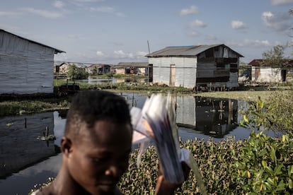 Un vendedor de películas camina por las casas en los pantanos alrededor de la isla Fredrick en Monrovia el 17 de noviembre de 2021.