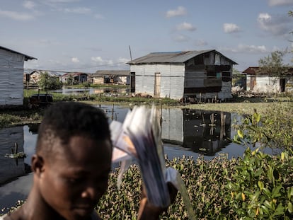 Un vendedor de películas camina por las casas en los pantanos alrededor de la isla Fredrick en Monrovia el 17 de noviembre de 2021.